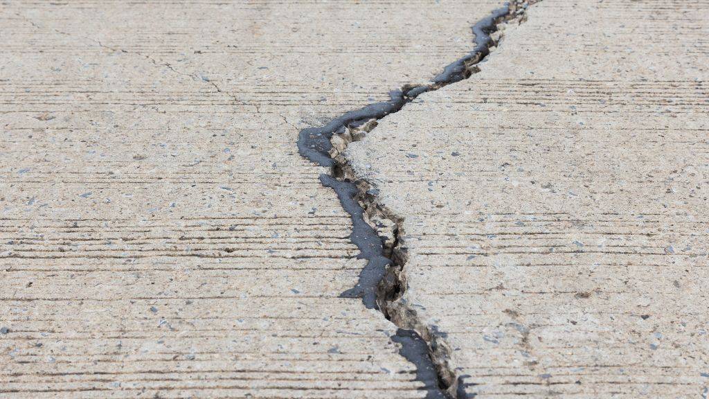 Heavy compaction rollers smoothing hot-mix asphalt during a summer driveway paving project in Heath and Rockwall TX