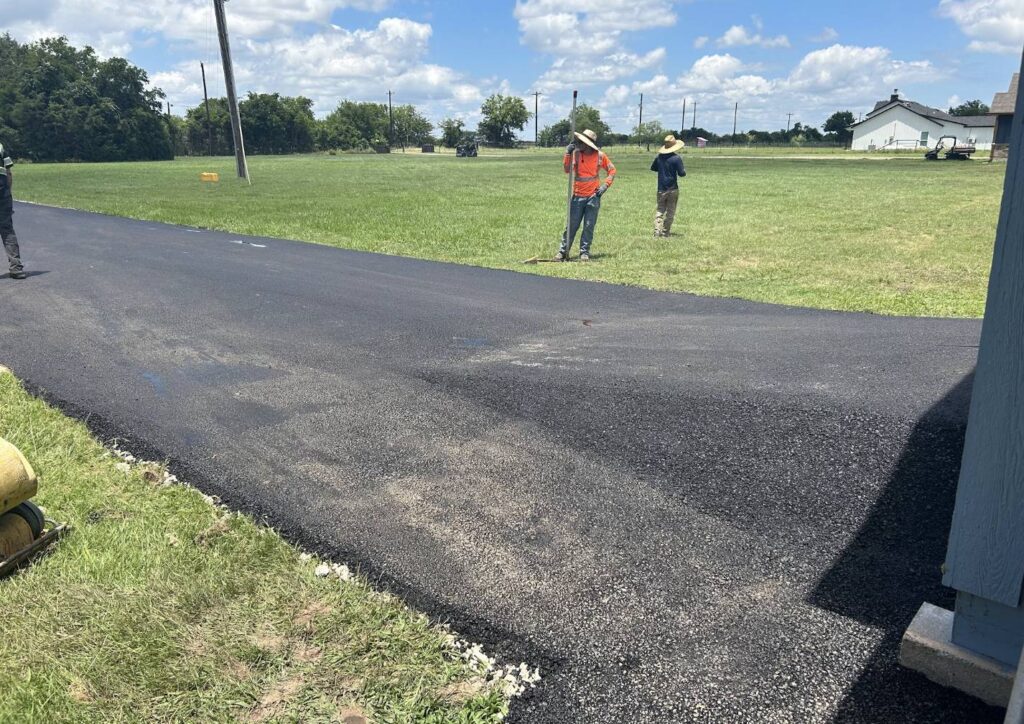 Paving crew taking measurements alongside a newly paved residential asphalt driveway in Rockwall TX.