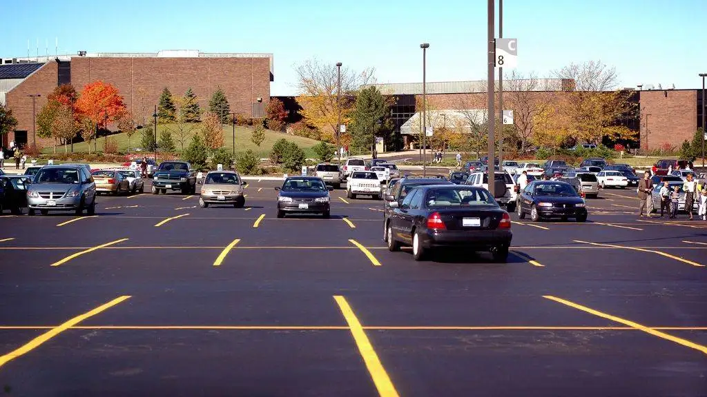 Freshly sealcoated commercial parking lot with bright yellow line striping outside a school facility in DFW.
