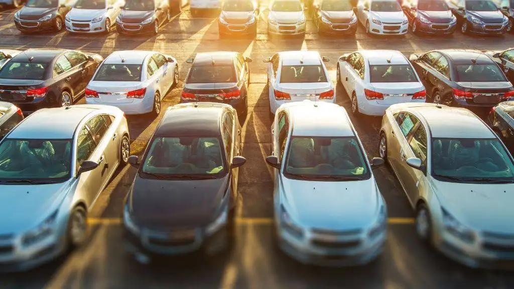 High-angle view of a busy commercial parking lot filled with parked cars during peak business hours in the DFW area.