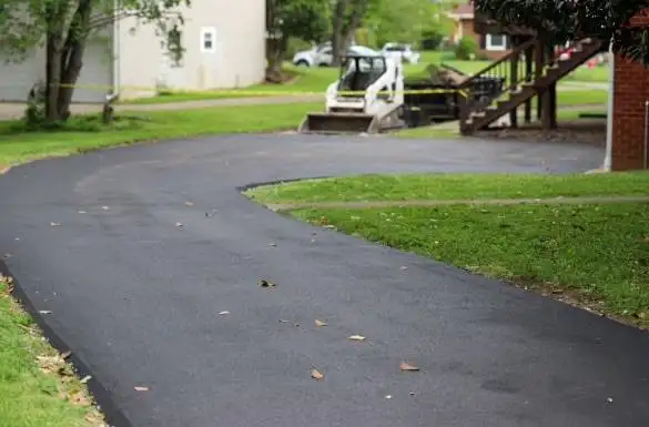Curved residential asphalt driveway freshly paved in a suburban Royse City TX neighborhood by Gentry's Paving Group.